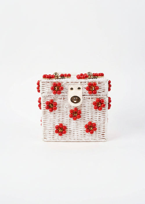 White handbag with red floral embellishments on a white background