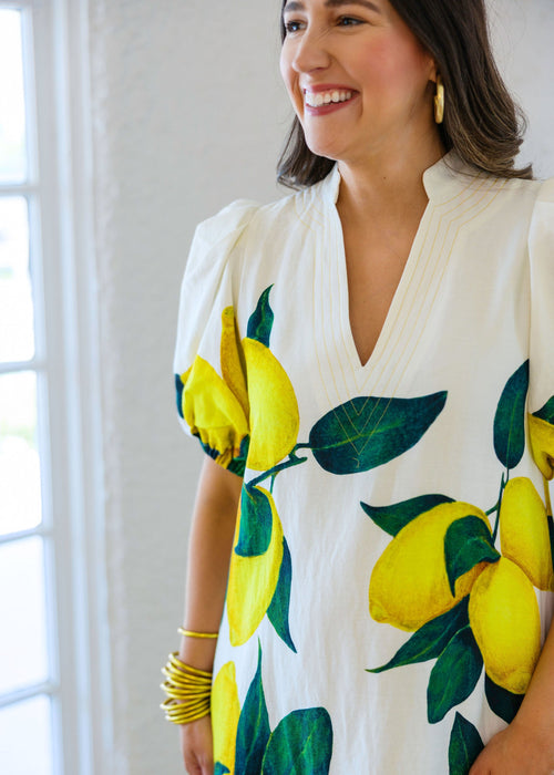 Woman wearing a white dress with lemon print in a bright indoor setting