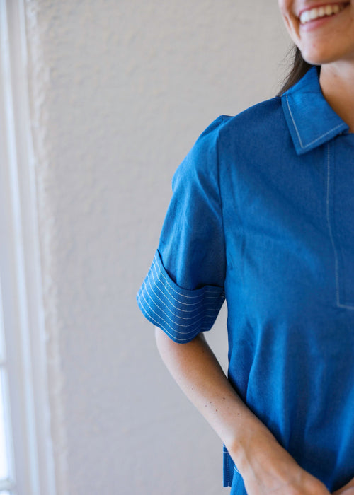 Person wearing a blue polo shirt against a neutral background