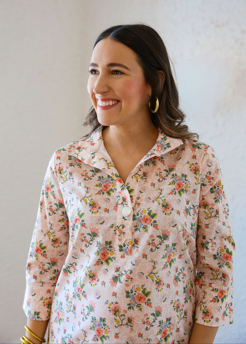 Woman wearing a floral blouse against a plain background