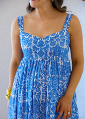 Woman wearing a blue and white patterned dress against a neutral background