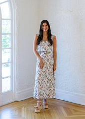 Woman in a floral dress standing in a room with a large window.