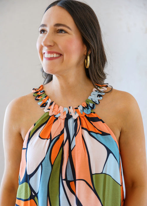 Woman wearing a colorful patterned dress against a plain background