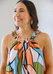Woman wearing a colorful patterned dress against a plain background