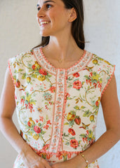 Woman wearing a floral sleeveless top against a plain background