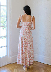 Woman in a floral dress standing in a room with a large window.