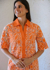 Woman wearing an orange patterned dress against a neutral background