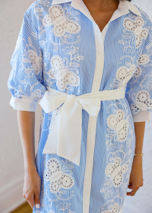 Blue and white striped dress with butterfly patterns and a white belt.