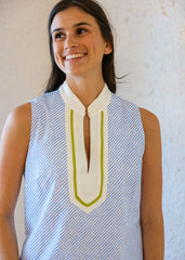 Woman wearing a sleeveless blouse with a white collar and green accents against a plain background