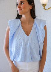 Woman wearing a blue and white striped sleeveless top against a plain background