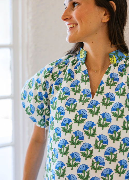 Woman wearing a floral patterned shirt with blue flowers on a white background