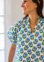 Woman wearing a floral patterned shirt with blue flowers on a white background