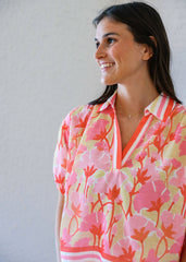 Woman wearing a colorful floral blouse against a plain background