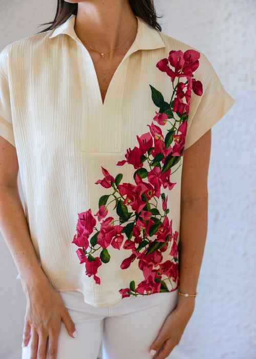 Woman wearing a cream-colored blouse with a floral design on a white background