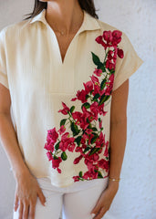Woman wearing a cream-colored blouse with a floral design on a white background