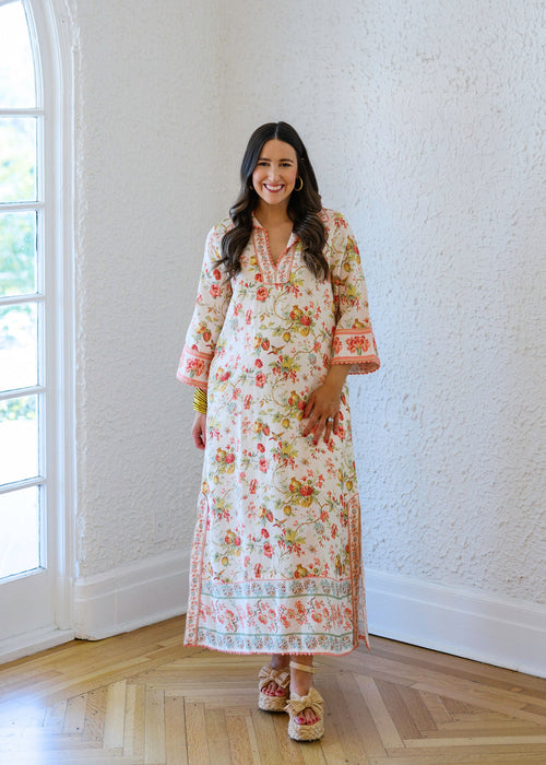 Woman in a floral dress standing in a room with a large window.
