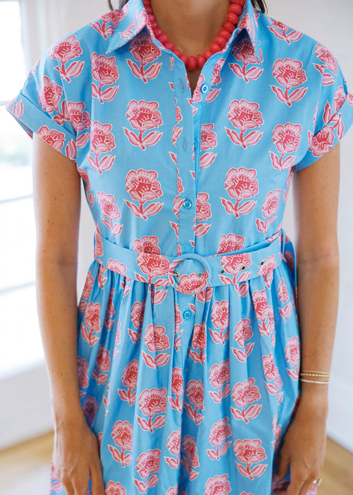 Person wearing a blue dress with pink floral pattern indoors
