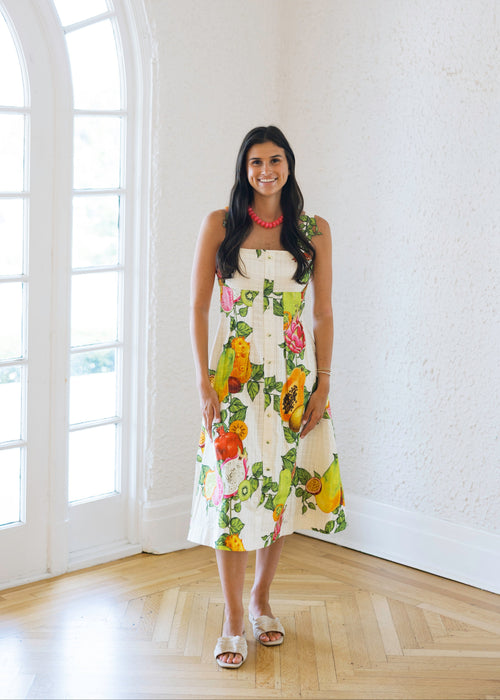 Woman in a floral dress standing in a bright room with large windows.