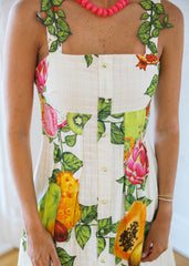 Person wearing a dress with a colorful fruit pattern on a white background