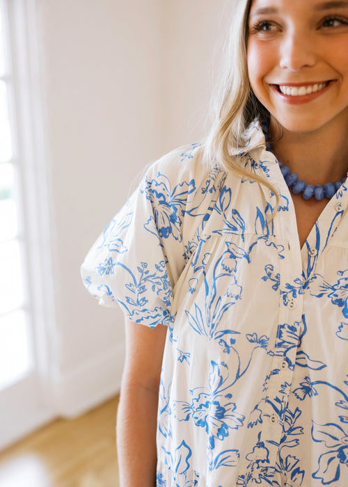 Woman wearing a white shirt with blue floral pattern indoors