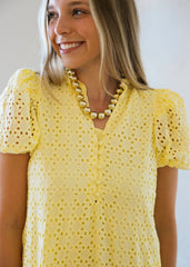 Woman wearing a yellow lace dress with a plain background