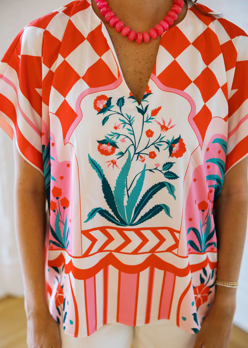 Person wearing a colorful floral and geometric patterned top with a blurred background