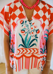 Person wearing a colorful floral and geometric patterned top with a blurred background