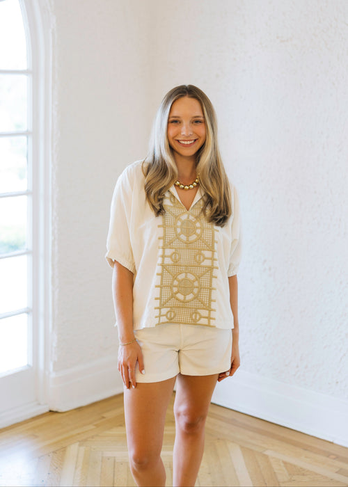Woman standing in a room with white walls and a large window.