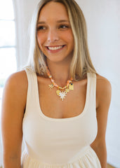 Woman wearing a white tank top and colorful necklace indoors