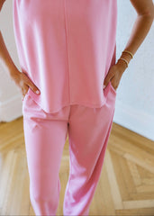 Person wearing a pink outfit with hands in pockets on a wooden floor.