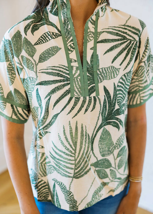 Person wearing a short-sleeve shirt with green leaf pattern on a white background
