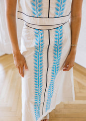 White dress with blue leaf patterns on a wooden floor
