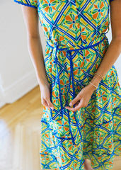 Person wearing a colorful patterned dress with blue accents on a light background