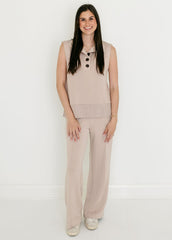 Woman wearing a beige sleeveless top and wide-leg pants on a white background