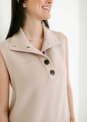 Woman wearing a beige sleeveless jacket with buttons on a white background