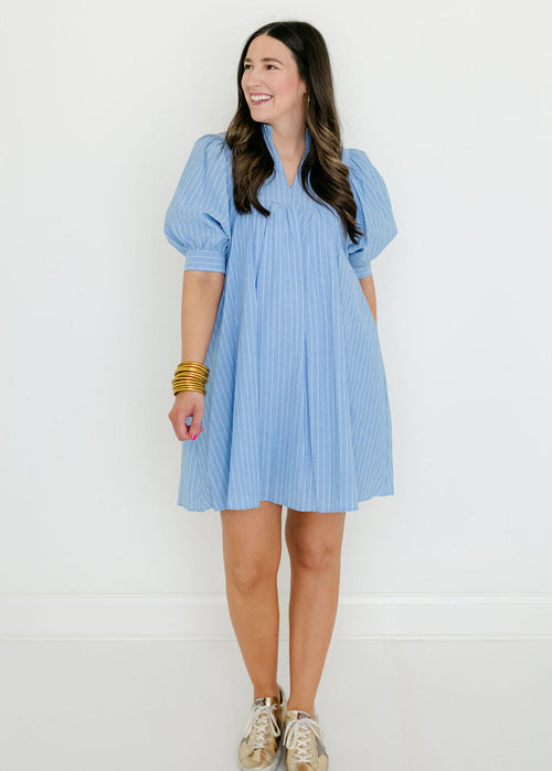 Woman wearing a light blue dress with puffed sleeves against a white background