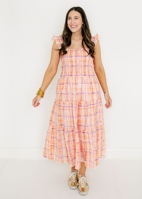 Woman wearing a plaid dress with pink and orange pattern on a white background