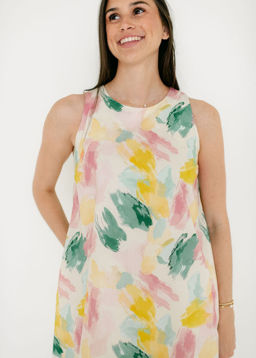 Woman wearing a sleeveless dress with colorful abstract pattern on a white background