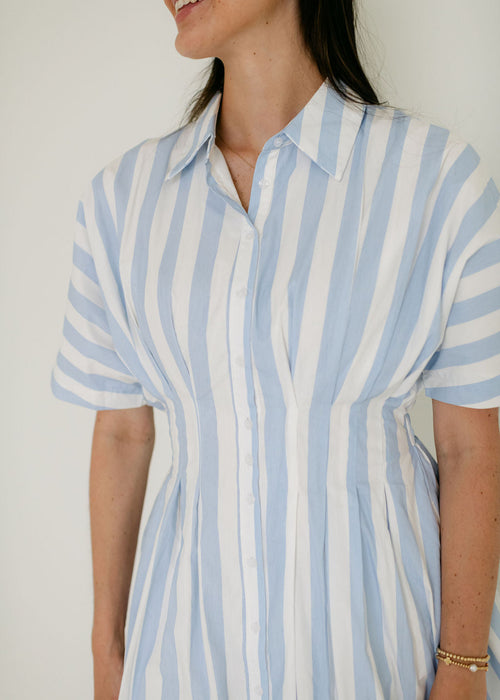Person wearing a blue and white striped shirt against a plain background