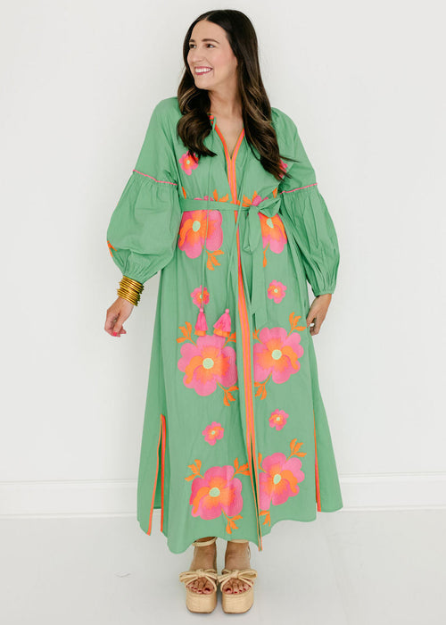 Woman wearing a green dress with floral embroidery on a white background