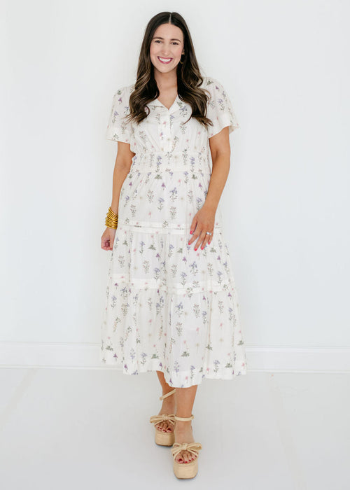 Woman wearing a white floral dress against a white background