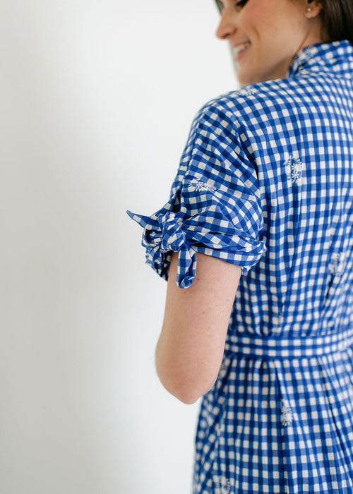 Woman wearing a blue and white checkered dress with a plain background