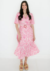 Woman wearing a pink dress with white pattern on a white background