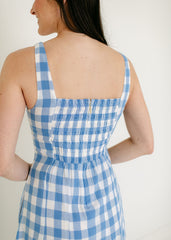 Woman wearing a blue and white checkered dress against a plain background