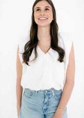 Woman wearing a white blouse and light blue jeans against a white background