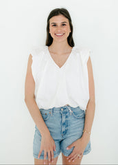 Woman wearing a white sleeveless top and denim shorts on a white background