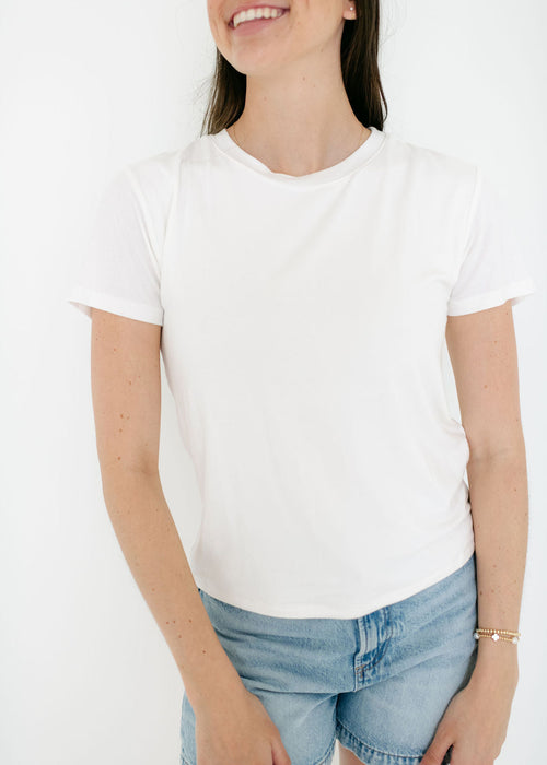Person wearing a plain white t-shirt and denim shorts on a white background