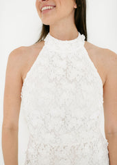Woman wearing a white lace halter top against a plain background