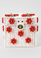 White woven handbag with red floral decorations on a light gray background